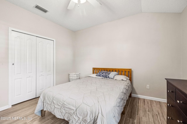 bedroom featuring baseboards, wood finished floors, visible vents, and a closet