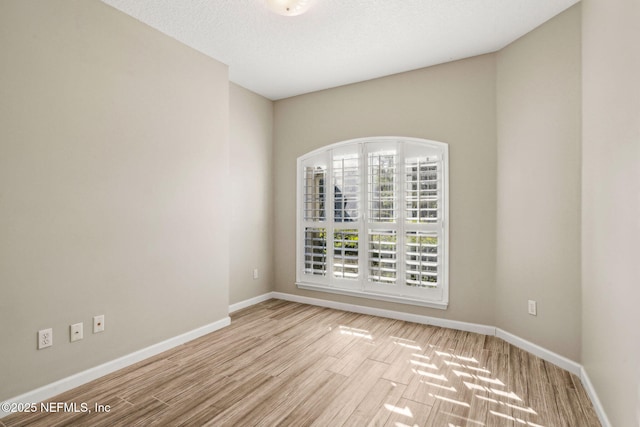 unfurnished room with baseboards and wood finished floors