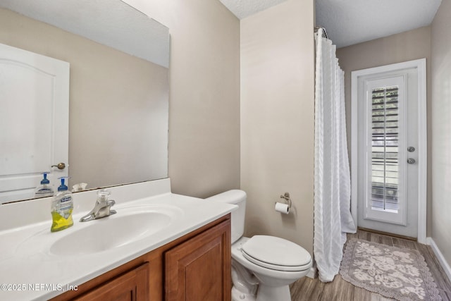 bathroom with toilet, a shower with shower curtain, vanity, and wood finished floors
