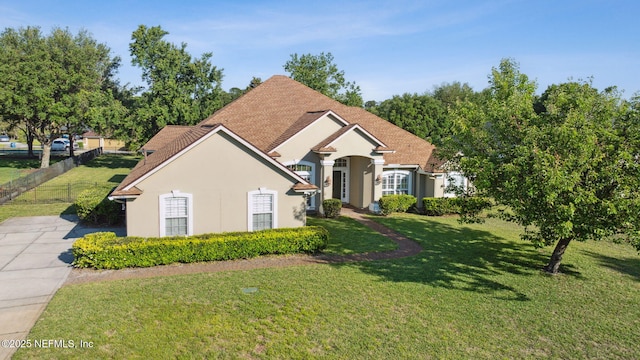 ranch-style house featuring a front lawn, stucco siding, and fence