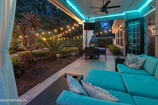 patio at night with a ceiling fan, outdoor dining area, and an outdoor living space