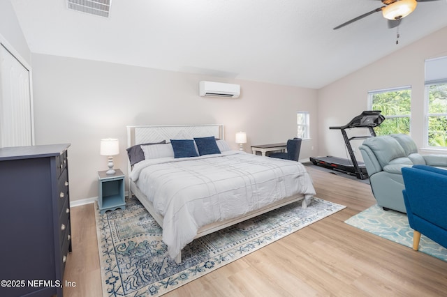 bedroom featuring a ceiling fan, a wall mounted AC, light wood-style flooring, lofted ceiling, and visible vents