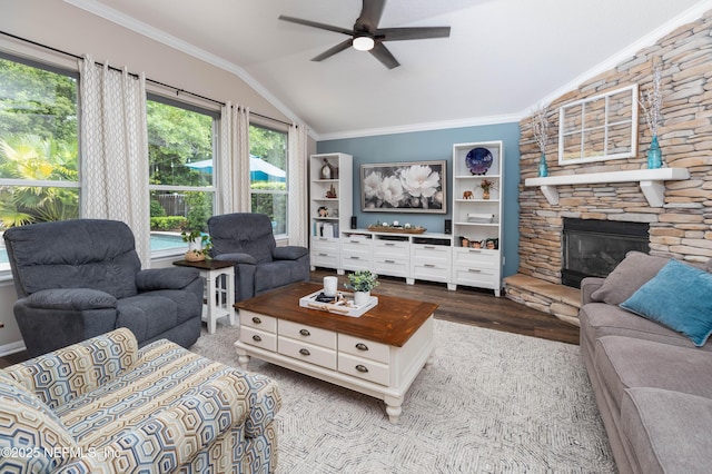 living room featuring lofted ceiling, a ceiling fan, wood finished floors, a stone fireplace, and ornamental molding