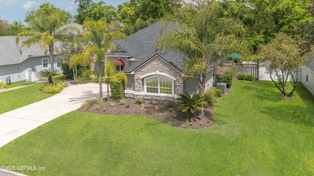 ranch-style house with central air condition unit, driveway, stone siding, fence, and a front yard