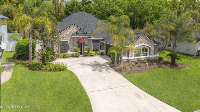 view of front of house featuring stone siding, concrete driveway, an attached garage, a shingled roof, and a front yard