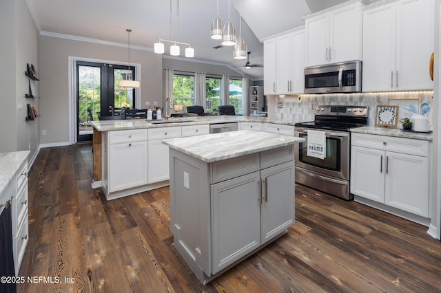 kitchen featuring a sink, a center island, a peninsula, tasteful backsplash, and appliances with stainless steel finishes