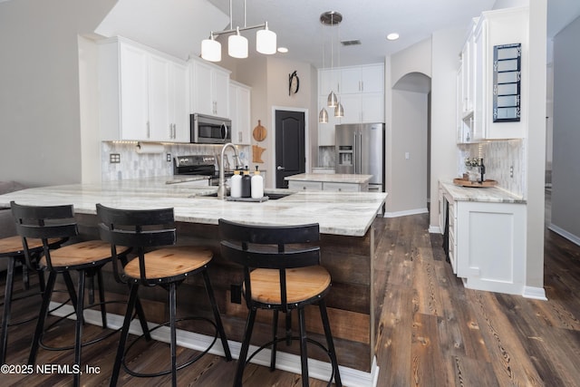 kitchen featuring a peninsula, backsplash, appliances with stainless steel finishes, and white cabinets