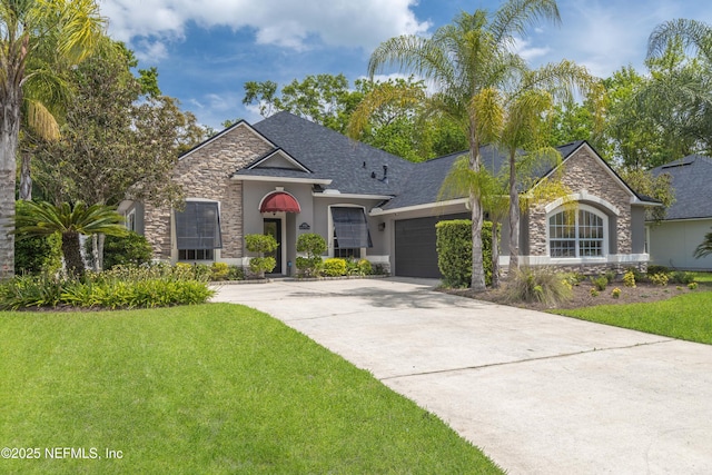 view of front facade featuring an attached garage, stone siding, a front yard, and driveway