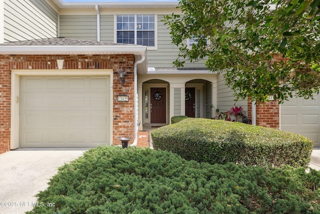 view of front of property with brick siding, driveway, and a garage