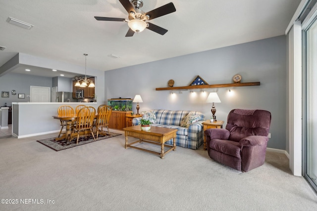 living room featuring visible vents, carpet, ceiling fan with notable chandelier, and baseboards