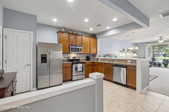 kitchen featuring a peninsula, appliances with stainless steel finishes, brown cabinetry, and visible vents