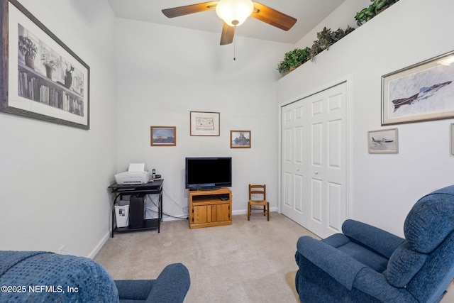 living area featuring a ceiling fan, baseboards, and light colored carpet