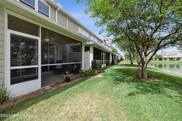 view of yard with a sunroom and a water view