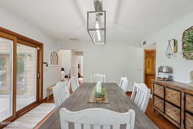dining room featuring a textured ceiling, visible vents, and dark wood-style floors