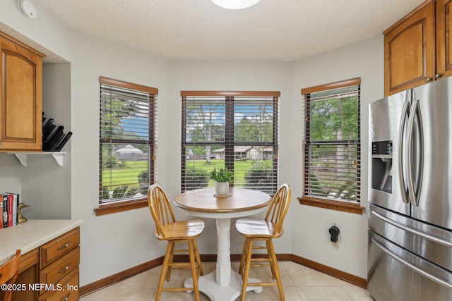 dining space featuring a textured ceiling, baseboards, and light tile patterned floors
