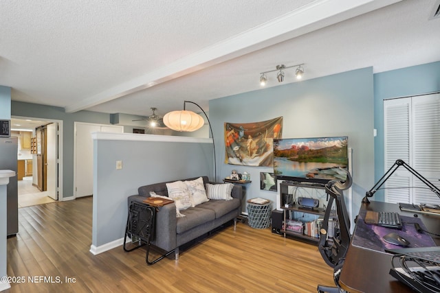 living room featuring a textured ceiling, baseboards, visible vents, wood finished floors, and beam ceiling