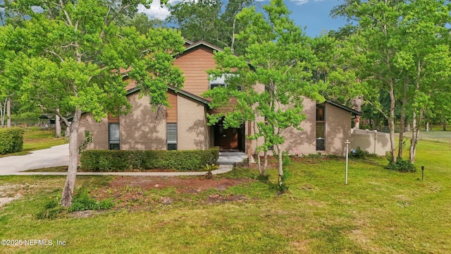 obstructed view of property with fence, a front lawn, brick siding, and concrete driveway