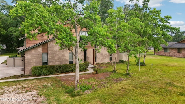 view of front of home featuring a gate, concrete driveway, a front lawn, and brick siding