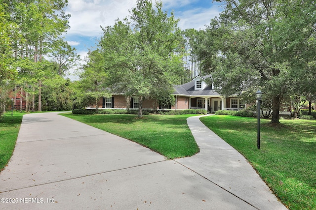 view of front facade with brick siding, driveway, and a front yard