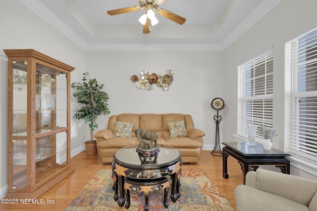 living room featuring light wood-style floors, a ceiling fan, baseboards, and a tray ceiling