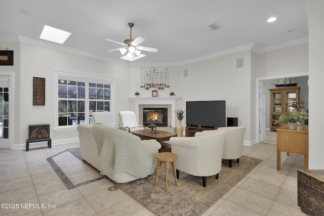 living room with visible vents, crown molding, a glass covered fireplace, and light tile patterned floors