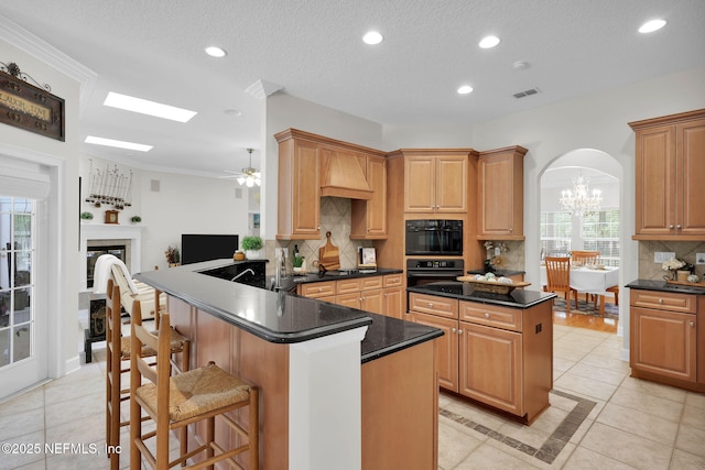 kitchen featuring dark countertops, arched walkways, a peninsula, light tile patterned floors, and visible vents
