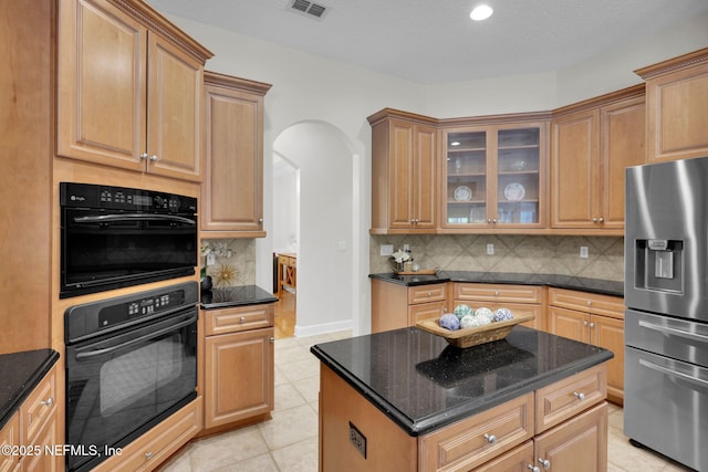 kitchen featuring stainless steel refrigerator with ice dispenser, arched walkways, backsplash, and visible vents