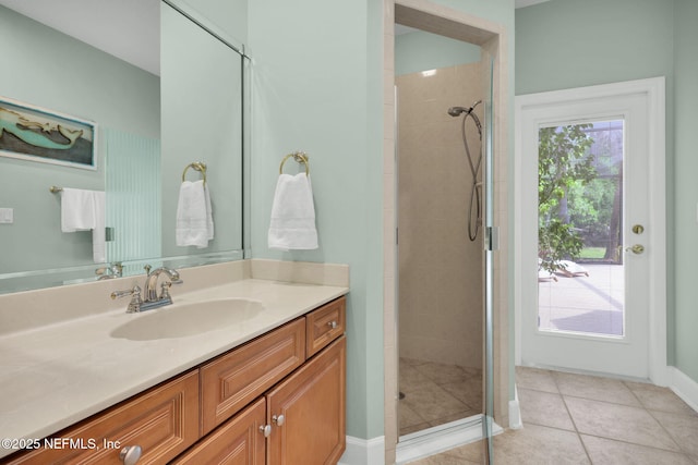 bathroom featuring baseboards, tiled shower, tile patterned flooring, and vanity