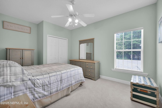 bedroom featuring baseboards, a ceiling fan, a closet, and light colored carpet