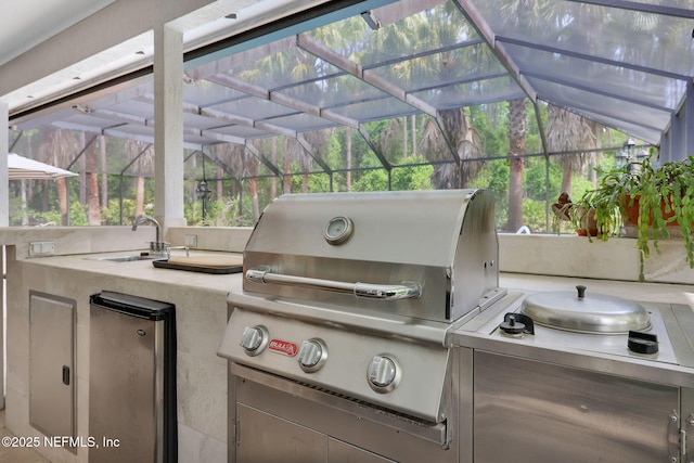 view of patio featuring a lanai, exterior kitchen, a sink, and a grill