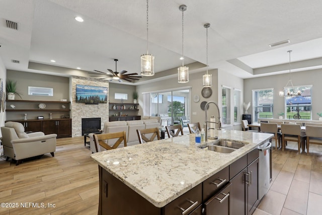 kitchen featuring a raised ceiling, hanging light fixtures, visible vents, and a sink