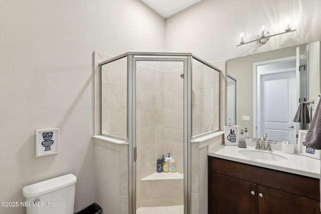 full bathroom with vanity, a shower stall, and toilet