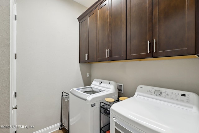 washroom featuring washing machine and clothes dryer, baseboards, and cabinet space