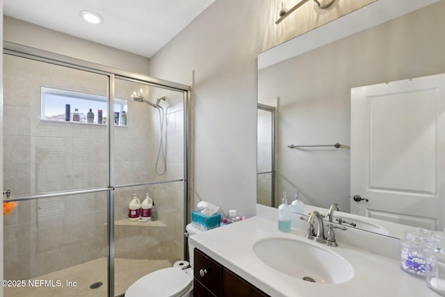 bathroom featuring a shower stall, toilet, and vanity