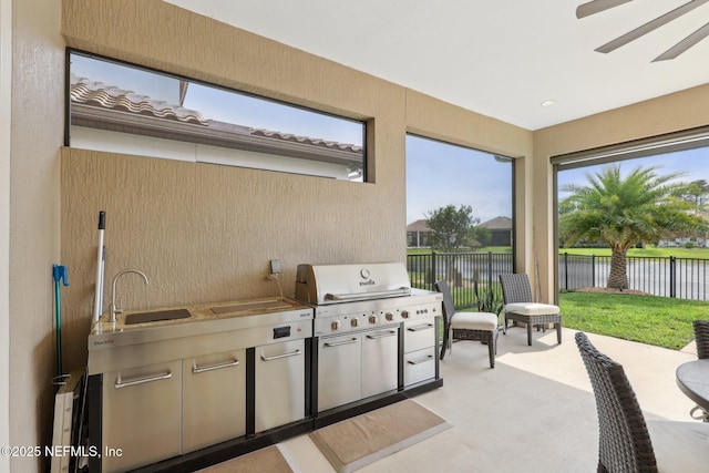 view of patio / terrace featuring a water view, a sink, fence, an outdoor kitchen, and area for grilling
