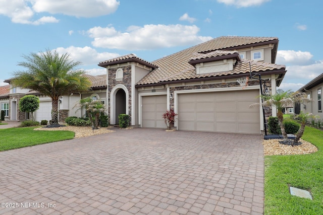 mediterranean / spanish-style house featuring stucco siding, decorative driveway, a tiled roof, and a garage