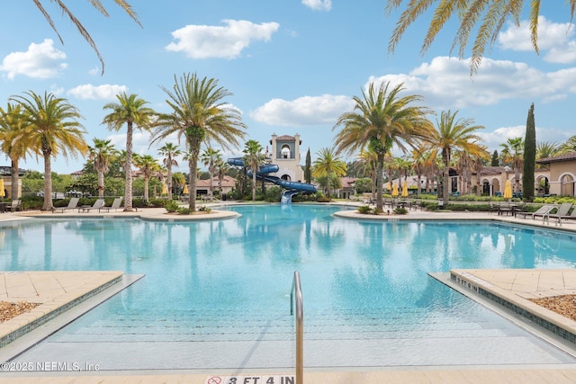 community pool with a water slide and a patio area