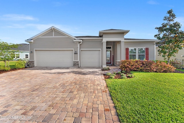 prairie-style house with a garage, stone siding, a front lawn, and decorative driveway
