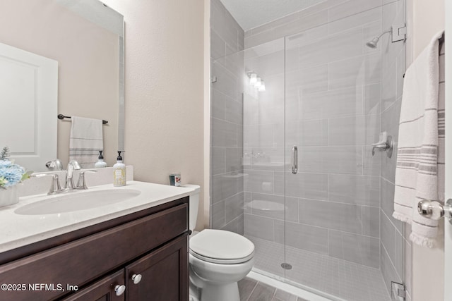 full bath with toilet, vanity, and a stall shower