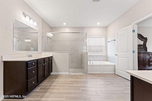 full bath with a bath, a tile shower, vanity, and wood tiled floor