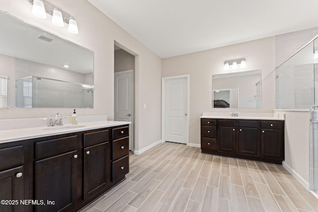 full bath with a shower stall, baseboards, a sink, and visible vents