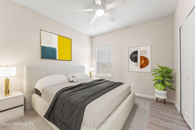 bedroom featuring ceiling fan, baseboards, wood tiled floor, and a closet