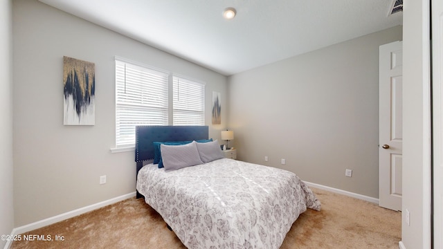 bedroom with baseboards, visible vents, and light colored carpet