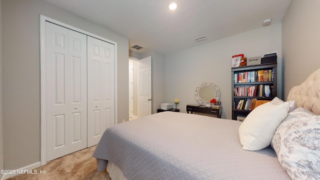 bedroom featuring a closet, visible vents, baseboards, and light carpet
