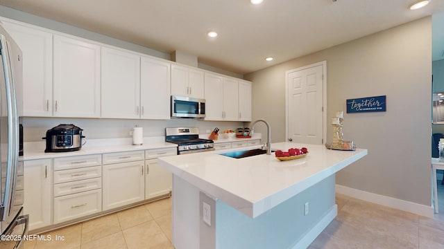 kitchen with white cabinets, a sink, light tile patterned flooring, an island with sink, and appliances with stainless steel finishes