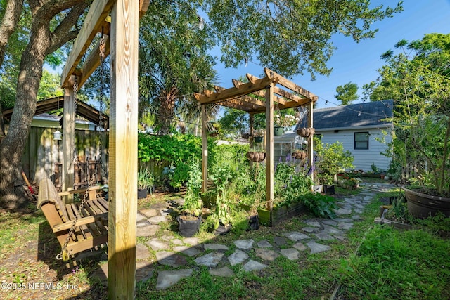 view of yard featuring a pergola, a vegetable garden, and fence