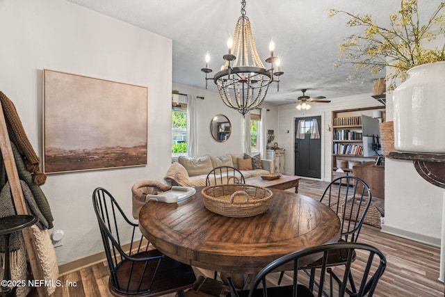 dining space featuring baseboards, wood finished floors, and ceiling fan with notable chandelier