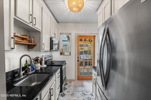 kitchen with dark stone countertops, decorative backsplash, appliances with stainless steel finishes, a sink, and baseboards