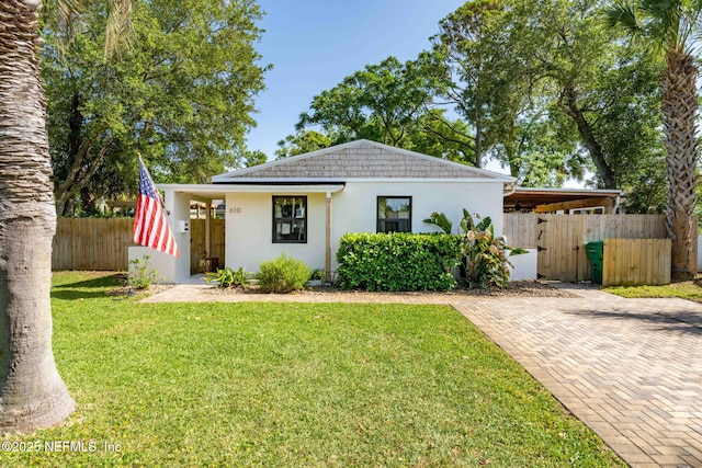 bungalow featuring stucco siding, fence, and a front yard