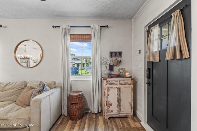 doorway to outside featuring dark wood finished floors, baseboards, an inviting chandelier, and a textured ceiling